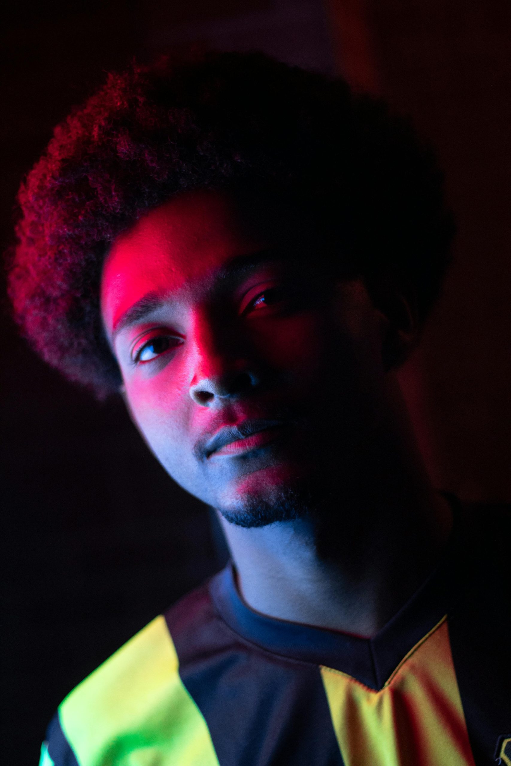 Striking portrait of a man with vibrant afro hair, captured in colorful neon lights.